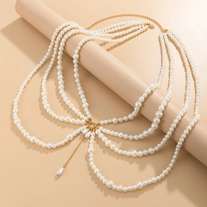 Multi-layer pearl body chain with golden alloy links and drop pendants on beige pedestal