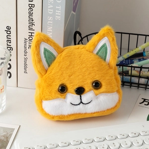 Close-up of orange plush fox coin purse with embroidery details on a cozy desk setup