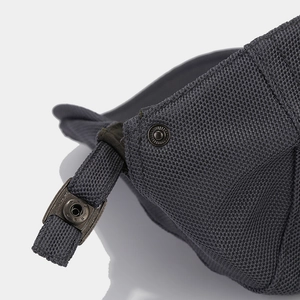 Macro shot of dark grey woven fabric with a bronze metal snap button and strap detail