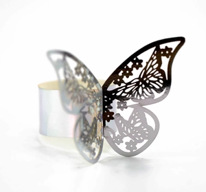 Macro shot of silver butterfly napkin ring with hollow carved wing patterns on white background