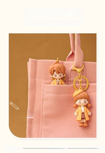 Close-up of cute cartoon couple keychains in school uniforms on a pink canvas bag