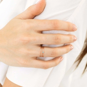 Detail of rose gold minimalist ring set featuring a light blue gemstone on model hand