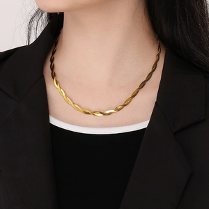 Detail view of a layered golden braided snake chain necklace worn by a fashion model