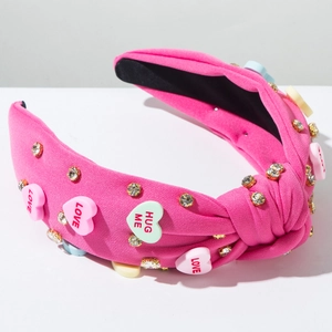 Detail of pink fabric headband with sparkling rhinestones and colorful heart candy charms