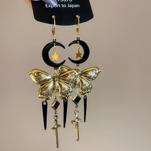 Détail de boucles d'oreilles vintage papillon avec lune et pendentifs d'épée dorés