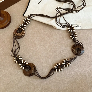 Detail of ethnic belt with brown rope, coconut shell discs and white wood beads
