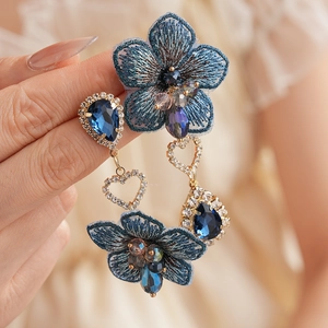 Détail de boucles d'oreilles fleurs brodées bleues avec cristaux vintage et cœurs dorés