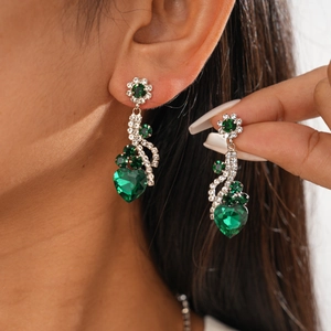 Détail de boucles d'oreilles fleur vintage et pendentif cœur vert avec strass brillants