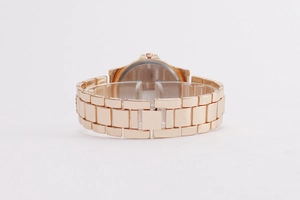 Detail view of the rose gold metal link strap and clean watch case back on a clear stand