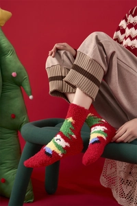 Detail of warm coral fleece Christmas socks featuring festive snowman and tree patterns