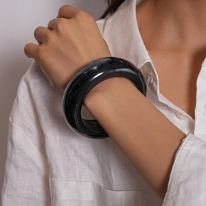 Macro detail of a wide black marble resin bangle bracelet on a female model