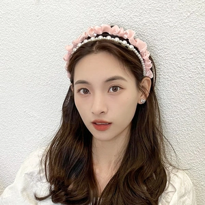 Close-up of pink pleated satin headband with pearl accents worn by a model