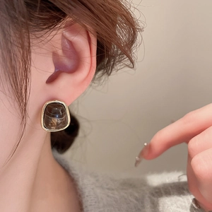 Close-up of vintage resin geometric stud earring in amber color with golden edge