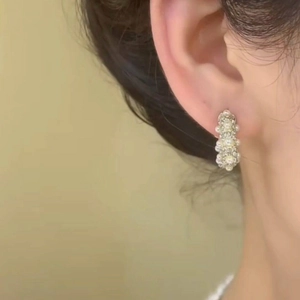 Macro view of gold-plated earrings with multiple pearls on a female ear