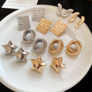 Detail view of assorted gold and silver geometric earrings on a white ceramic tray