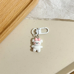 Dettaglio di un portachiavi a forma di orso bianco con fiocco rosa su vassoio in legno