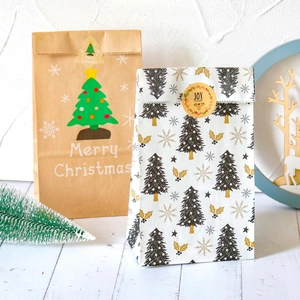 Christmas kraft paper bags with festive tree designs and holiday seals on white wood