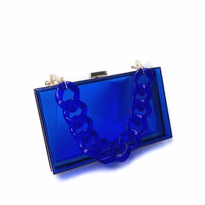 Detail view of royal blue acrylic evening bag featuring chunky chain and gold metal clasp