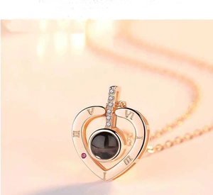 Detail of rose gold heart pendant with projection stone and Roman numeral engraving