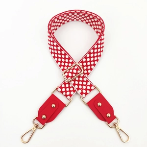 Close-up of red and white jacquard wide shoulder strap with gold swivel hooks