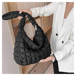 Close-up of black quilted bubble shoulder bag with a glossy nylon texture on model