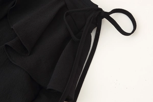 Close-up of black ruffled layered dress fabric with tie-up detail and textured chiffon material