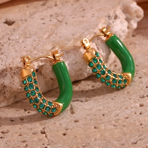 Macro shot of U-shaped gold earrings with green enamel coating and micro-set zircons