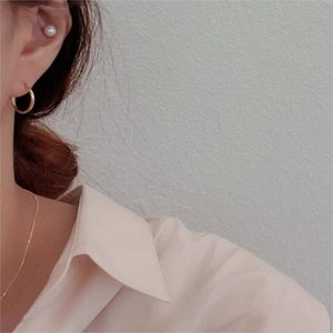 Detailed view of elegant gold hoop earrings and pearl studs worn with a minimalist necklace