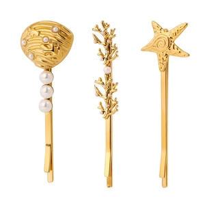 Détail des barrettes en acier doré 18 carats avec motifs de coquillage, corail et étoile