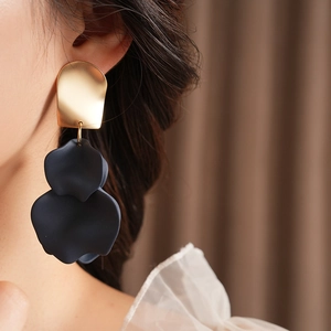 Detail of irregular flower earrings with gold metal and matte black petals on model