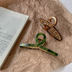 Large acetate hair claw clips with tortoise pattern and gold alloy splicing on paper background