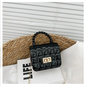 Detail of black PVC jelly bag with gold hardware and chain on a book background