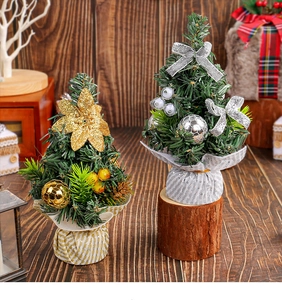 Mini Christmas trees with gold flowers and silver bows on dark wooden tabletop