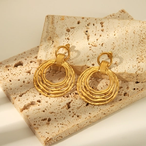 Détail de boucles d'oreilles dorées irrégulières à plusieurs couches sur pierre naturelle