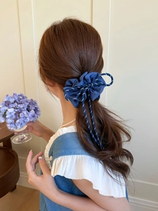 Detail of blue plaid fabric scrunchie with bow tie design worn by a model in a ponytail