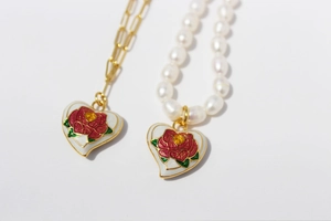 Detail of vintage enamel heart pendants with red roses on pearl and paperclip chains