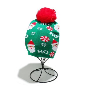 Detail of green Christmas beanie featuring Santa embroidery and a large red pompom