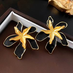 Detailed macro view of vintage black and gold flower earrings with polished enamel finish
