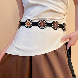 Close-up of vintage ethnic leather belt featuring geometric floral patterns and silver studs
