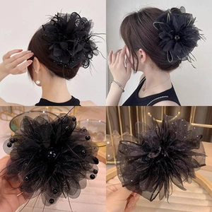 Detail of black mesh flower hair accessory with elegant pearl and feather embellishments