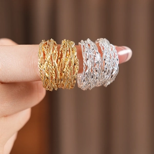 Close-up of twisted 18K gold and silver plated C-shape earrings with woven texture