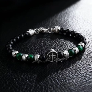 Macro shot of 6mm black and green tiger eye stone beads with silver cross charm bracelet
