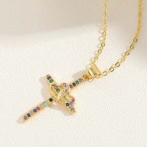 Close-up of golden cross pendant featuring multicolored cubic zirconia and interlinked hearts
