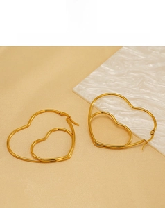 Détail des boucles d'oreilles double cœur évidé en acier inoxydable doré sur marbre