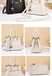 Close-up of the black and white handbag with golden hardware and cherry pendant detail