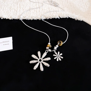 Detail view of silver daisy charms and brown tiger eye beads on a fashion necklace