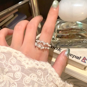 Dettaglio di anello a doppio strato con perle e zircone a stella su mano con pizzo