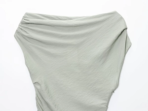 Détail du tissu en maille vert sauge clair montrant d'élégants plis drapés sur le côté