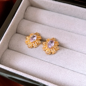 Makroaufnahme vergoldeter Blumenohrstecker mit violettem Edelstein und Kristallen