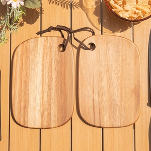Top view of two oval acacia wood cutting boards with leather hanging straps on a table